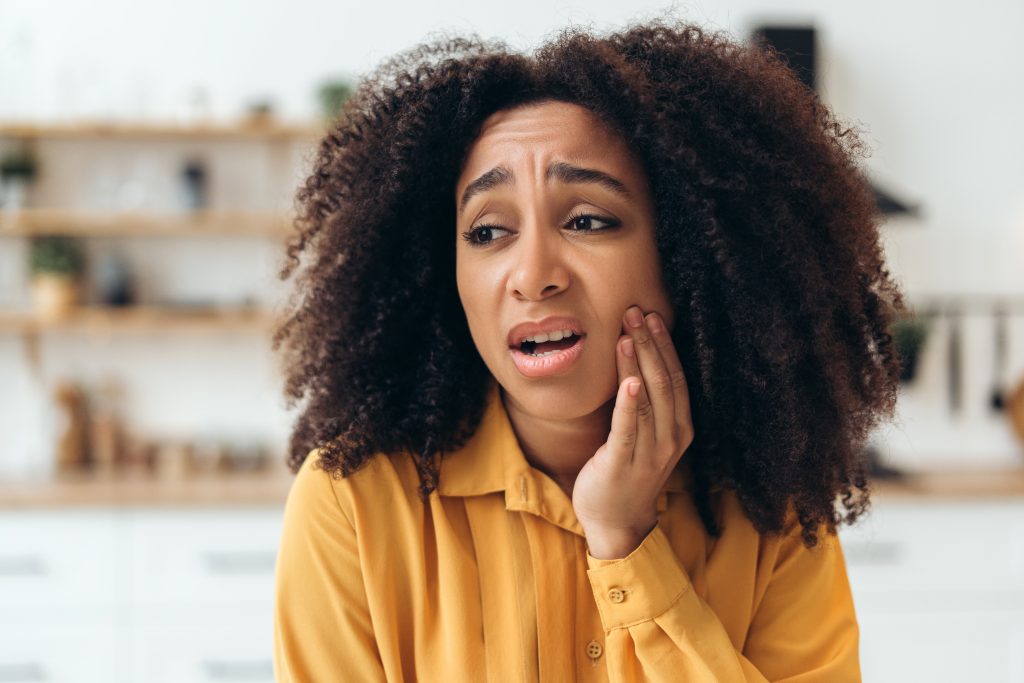 Young Woman Suffering From Toothache Touching Cheek at Home